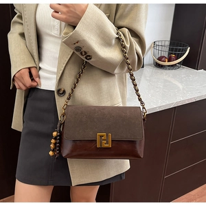 Detail of vintage brown leather crossbody bag with metal chain and wooden bead charm
