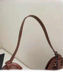 Detail of smooth leather shoulder strap and leopard print faux suede on tote bag