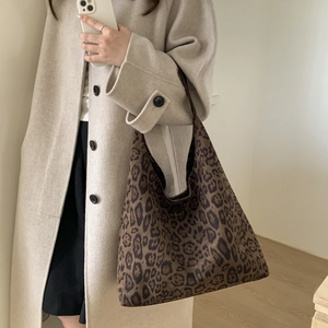 Detail of large leopard print hobo bag worn by model in a minimalist studio setting