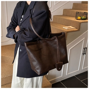 Large dark brown tote bag with glossy leather texture and stylish shoulder strap detail