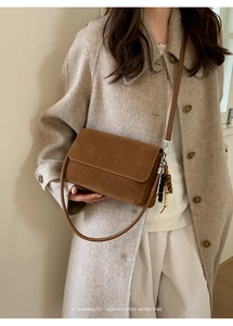 Detail view of brown suede crossbody bag with decorative wooden beads on a model