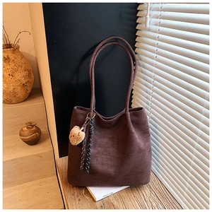 Close-up of vintage brown suede tote bag with cute plush bear pendant and soft textures