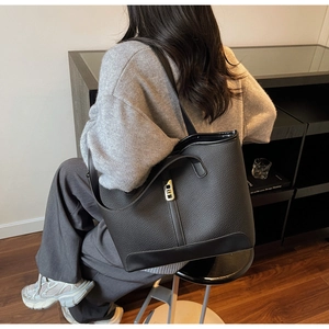 Détail d'un cabas noir en cuir grainé avec une boucle métallique dorée élégante