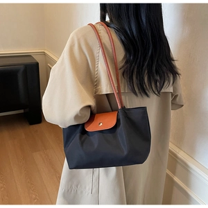 Detail shot of a black nylon shoulder bag with brown leather flap and silver buckle
