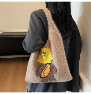 Detail of plush brown knit tote bag with a cute bear patch embroidery and yellow hat