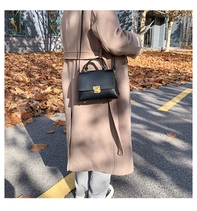 Detail of vintage black leather square bag with gold metal clasp and sturdy top handle