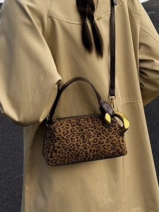 Luxury leopard print cylinder shoulder bag with gold metal ring on a khaki trench coat