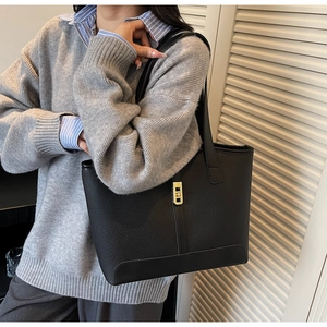 Détail du sac cabas en cuir grainé noir avec boucle en métal doré pour un style chic urbain