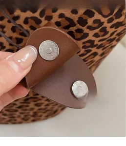 Detail of silver magnetic buckle on leopard print suede tote with brown leather strap