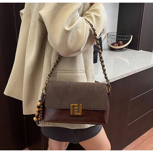 Detail of vintage brown shoulder bag with gold geometric clasp and wooden bead tassel