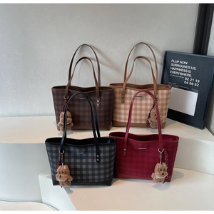 Detail of four checkered tote bags with plush bear charms in various autumn colors