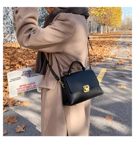 Sac à main classique en cuir noir doté d'une boucle métallique dorée sur le rabat avant