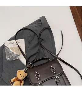 Detail of dark brown vintage faux suede crossbody bag with smooth adjustable strap