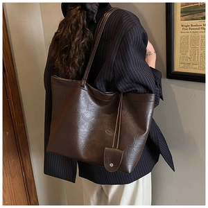 Brown faux leather tote bag with magnetic clasp shown on a model in a retro suit