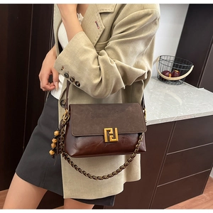 Detail of vintage brown shoulder bag with gold clasp, wooden beads and chain strap