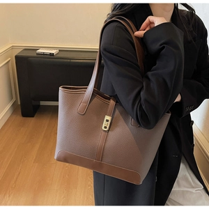 Détail d'un sac cabas en cuir grainé marron foncé avec boucle dorée et bandoulière