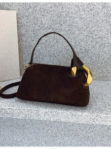 Elegant dark brown suede Boston bag with large gold hardware on grey stone background