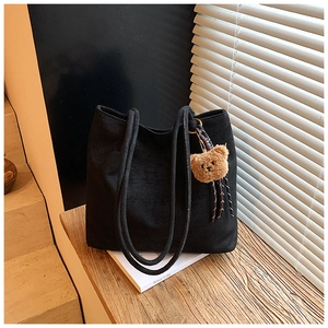Detail of black large capacity vintage tote bag with a cute plush bear charm accessory