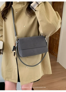 Detail of grey suede crossbody bag with retro wooden bead tassel and minimalist flap cover