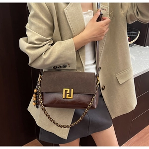 Detail of vintage brown patchwork crossbody bag featuring golden geometric metal buckle