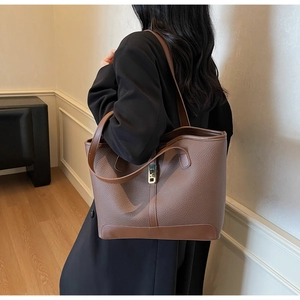Détail d'un sac cabas en cuir marron avec motif litchi et boucle métallique dorée chic