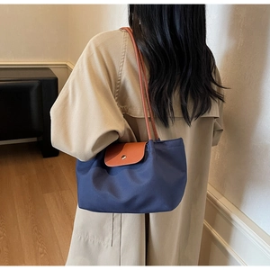Detail of navy nylon tote with brown leather flap and golden button closure