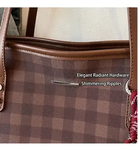 Detail of checkered tote bag featuring polished silver metal bar and red woven charm