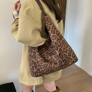 Detail view of large leopard print tote bag showing side profile and shoulder strap on model