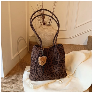 Macro detail of leopard print canvas tote bag with brown straps and plush bear charm