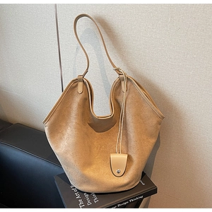 Détail d'un grand sac cabas en daim camel avec serrure en métal sur des livres anglais