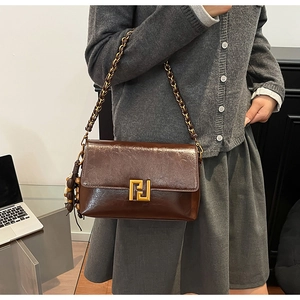Detail of vintage brown leather handbag with gold buckle and beaded tassel charm