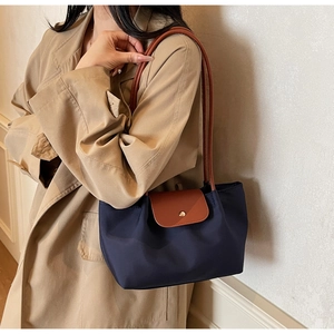 Detail of navy nylon tote bag with brown leather flap and golden button closure