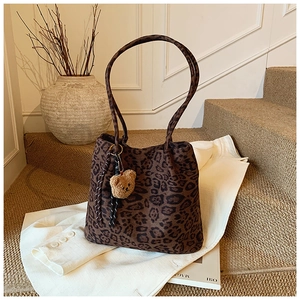 Close-up of leopard print tote bag with brown bear charm in an autumn setting