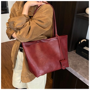 Detail view of the large capacity burgundy tote bag with vintage leather texture and side charm