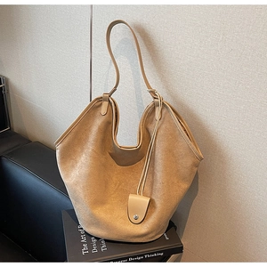 Vue détaillée du sac cabas en daim kaki sur canapé cuir avec bandoulière élégante