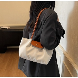 Detail of white tote bag with brown leather handles and gold snap closure