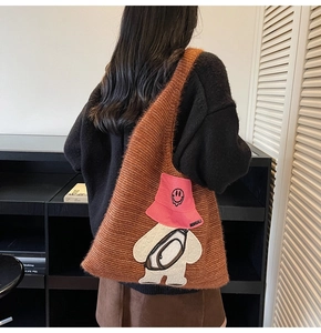 Close-up of deep orange knit tote bag featuring a cute cartoon bear patch embroidery