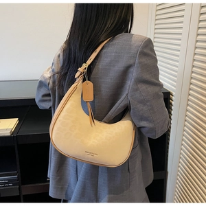 Detailed view of a beige crescent hobo bag with adjustable strap on a plaid blazer