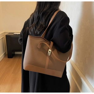 Détail d'un sac cabas en cuir grainé marron caramel avec fermoir rotatif doré élégant