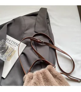 Detail view of the brown plush bucket bag showing the adjustable leather shoulder strap texture
