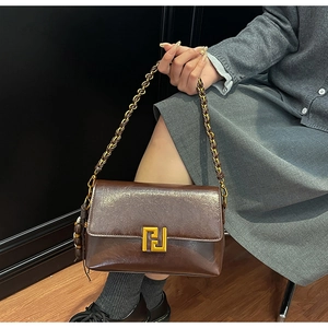 Detail of vintage brown leather handbag with gold geometric buckle and chain strap