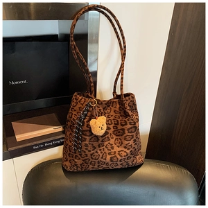 Detail of leopard print tote bag with plush bear charm and striped rope tassel decoration