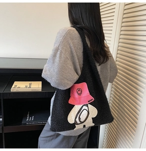 Detail of black fuzzy tote bag featuring a cute cartoon character embroidery with pink accents