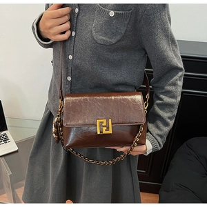 Macro detail of brown glossy leather bag with gold geometric metal buckle and strap