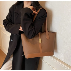 Vue détaillée du sac cabas en cuir marron caramel avec fermoir doré porté par un mannequin