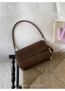 Detail shot of a dark brown suede crossbody bag with minimalist retro wooden bead charm