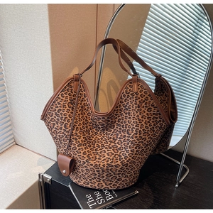 Détail du sac cabas léopard avec anses en cuir marron et une petite pochette assortie