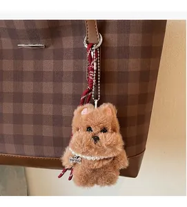 Brown plush dog keychain with pearl necklace on a checkerboard patterned tote bag