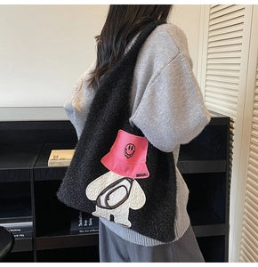 Detail of black fleece tote bag featuring a cute bear patch embroidery with pink bucket hat