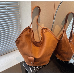 Détail du grand sac cabas en daim marron avec silhouette en V et pendentif à bouton-pression